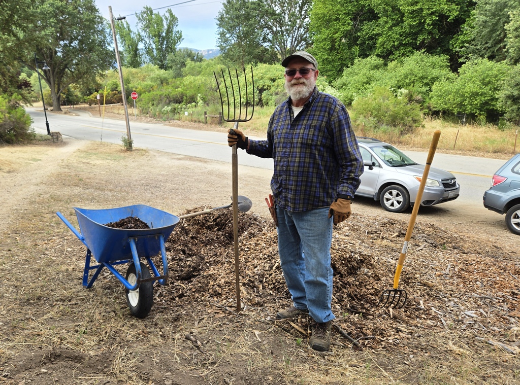 Cory loading up a wheelbarrow with mulch.